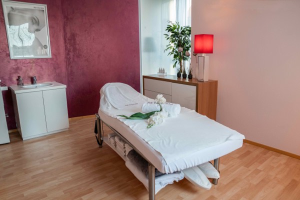 Behandlungsraum mit weinroter Wand und frischen Orchideen